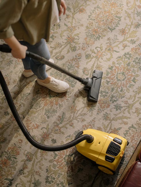 A close-up view of a patterned carpet in a bedroom, featuring a brown base colour with white intersecting lines forming a grid pattern. The room has natural light coming through large window panes, pa